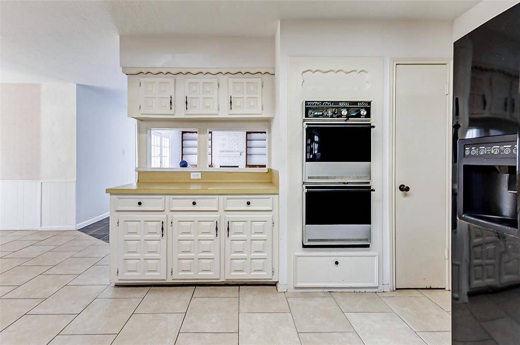 Opposite the sink, you'll find double ovens, a pantry, and additional counter and cabinet space, providing ample room for both storage and meal preparation.