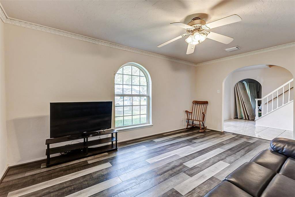 An alternate view highlights the beautiful arched window, offering a picturesque view of the front yard. The room provides ample space for a sofa and chairs, or even a sectional, and could easily serve as a versatile flex space.