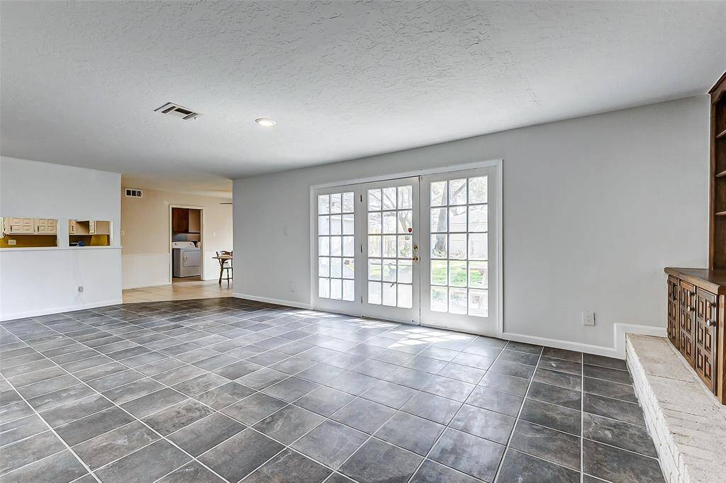 Continuing from the entryway, you'll find the spacious family room, featuring French doors that frame views of the expansive backyard, creating a seamless flow between indoor and outdoor living spaces.