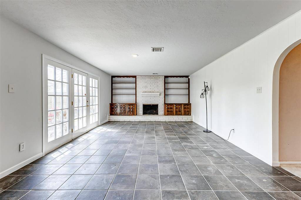Unwind beside the cozy fireplace, featuring a striking brick surround that extends to the ceiling. The fireplace is beautifully flanked by original solid wood built-ins, adding both charm and functionality to the space.