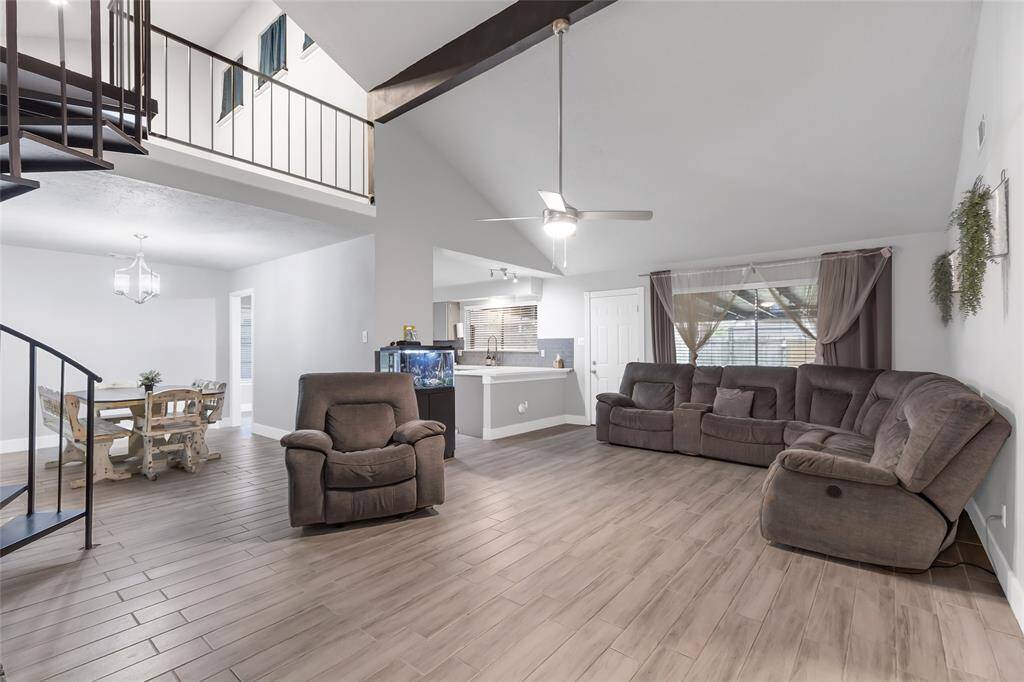 Large open concept family room with vaulted ceiling, wood beam and large windows providing natural light.