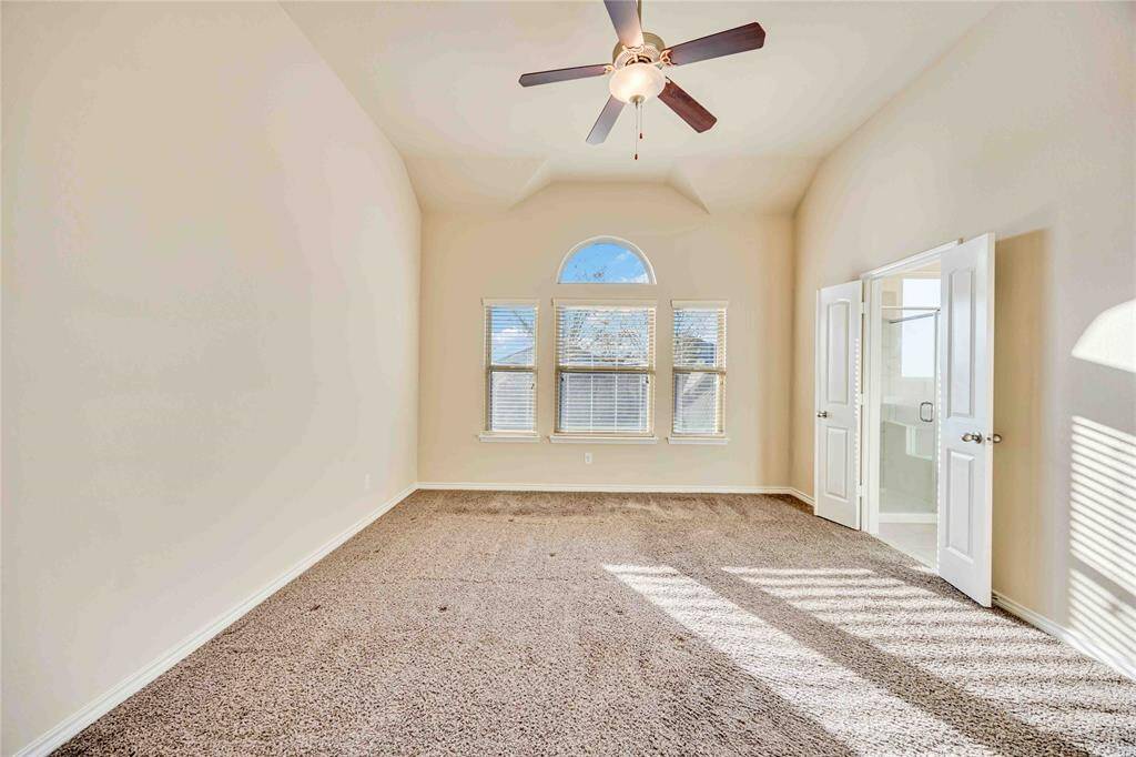 This spacious bedroom features high ceilings, a large arched window for natural light.