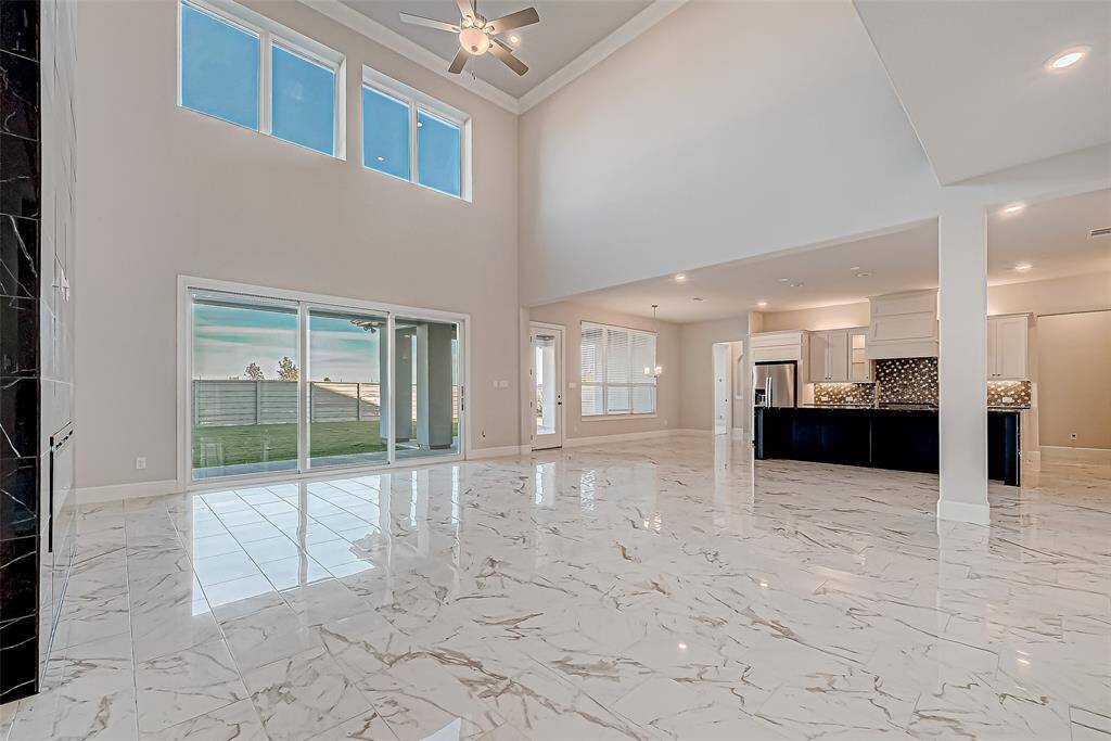 The extended family room is a centerpiece of comfort and modern design. Floor-to-ceiling tiled electric fireplace with color-changing capability takes center stage, while large windows flood the space with natural light.