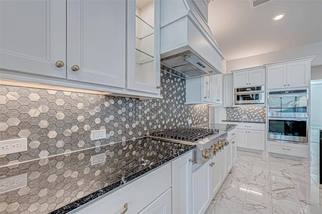 Top-of-the-line stainless steel appliances include a six-burner gas cooktop with gold accents, double ovens, and a convection microwave.