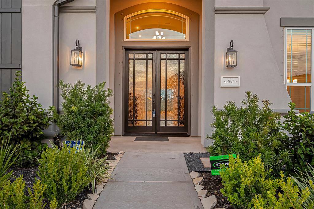 An inviting covered porch entryway featuring elegant double wood doors with rain glass panels.