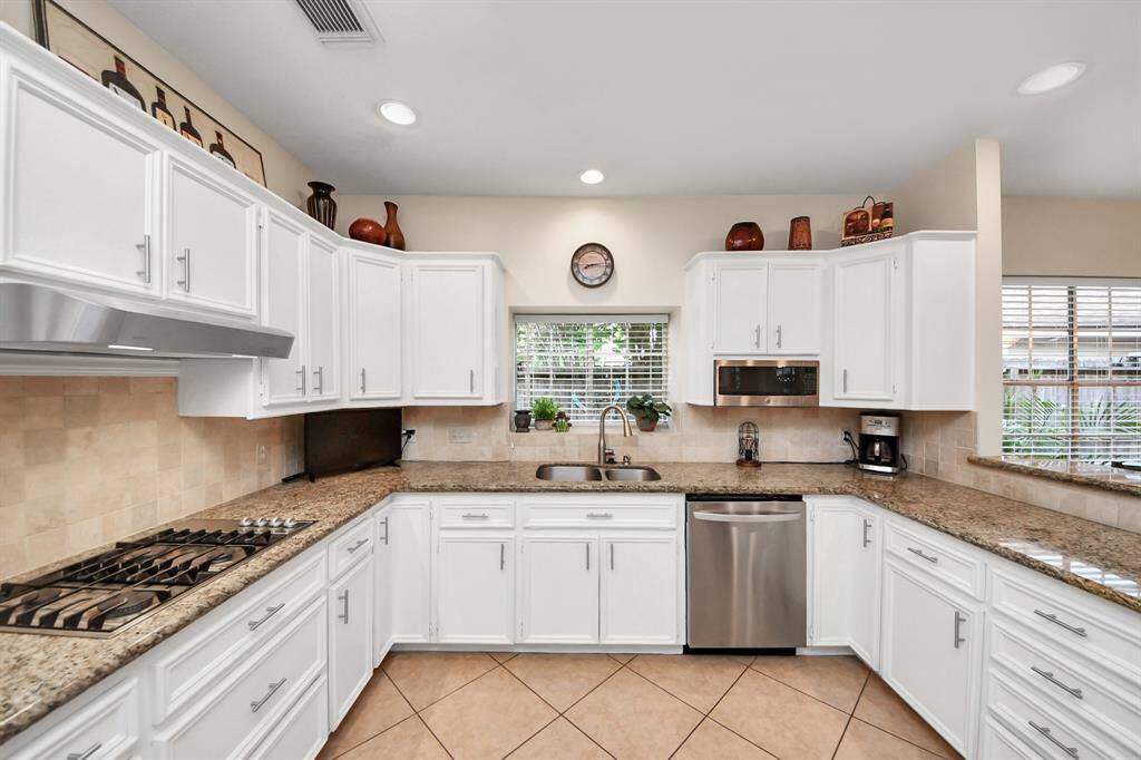 The kitchen is truly impressive, showcasing granite countertops, crisp white cabinetry, and a sleek gas cooktop—making this a gourmet culinary space.