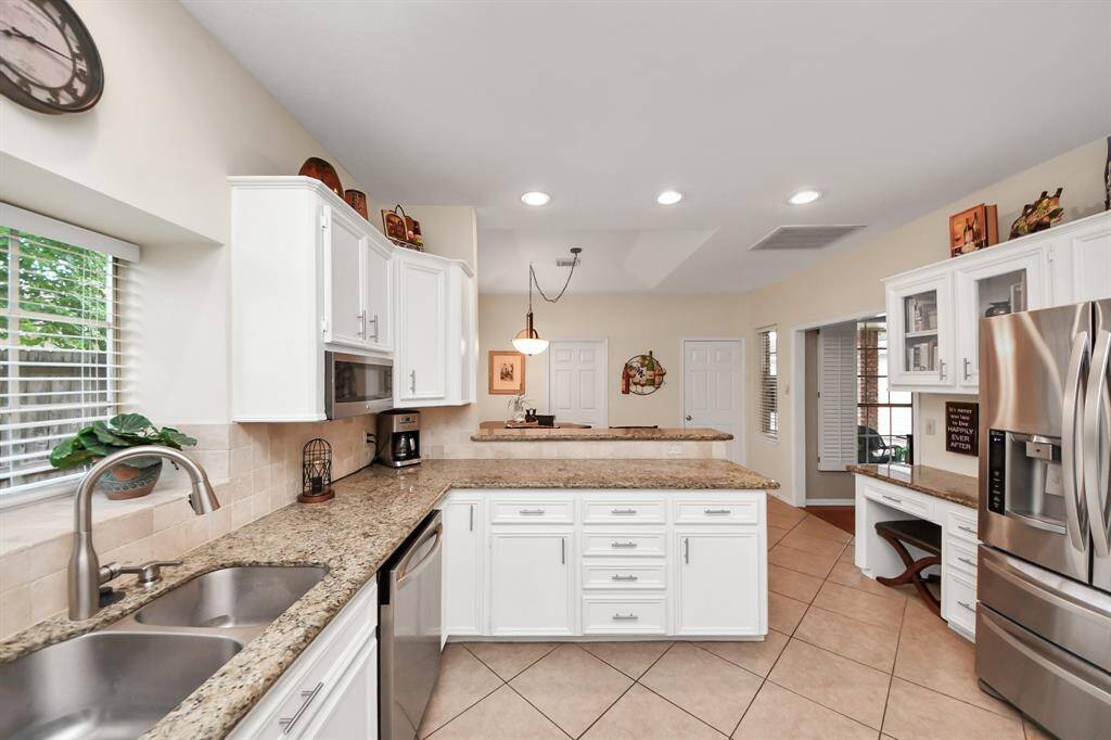 The kitchen is equipped with stainless steel appliances, including a dishwasher, sink, and built-in microwave. A dedicated desk area offers the perfect space for paying bills, completing homework, or tackling household tasks.