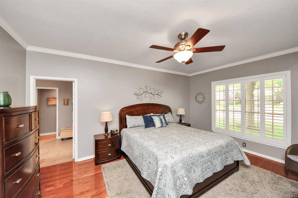 The primary bedroom, located downstairs, is a true owner’s suite—a serene retreat offering privacy and comfort. It features a neutral paint palette, elegant shutters, and beautiful wood floors that enhance the tranquil atmosphere.