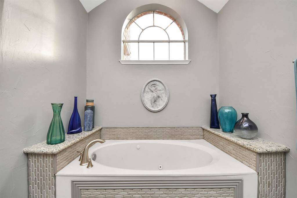 A jetted tub with elegant tilework provides the perfect setting for a long, soothing soak.