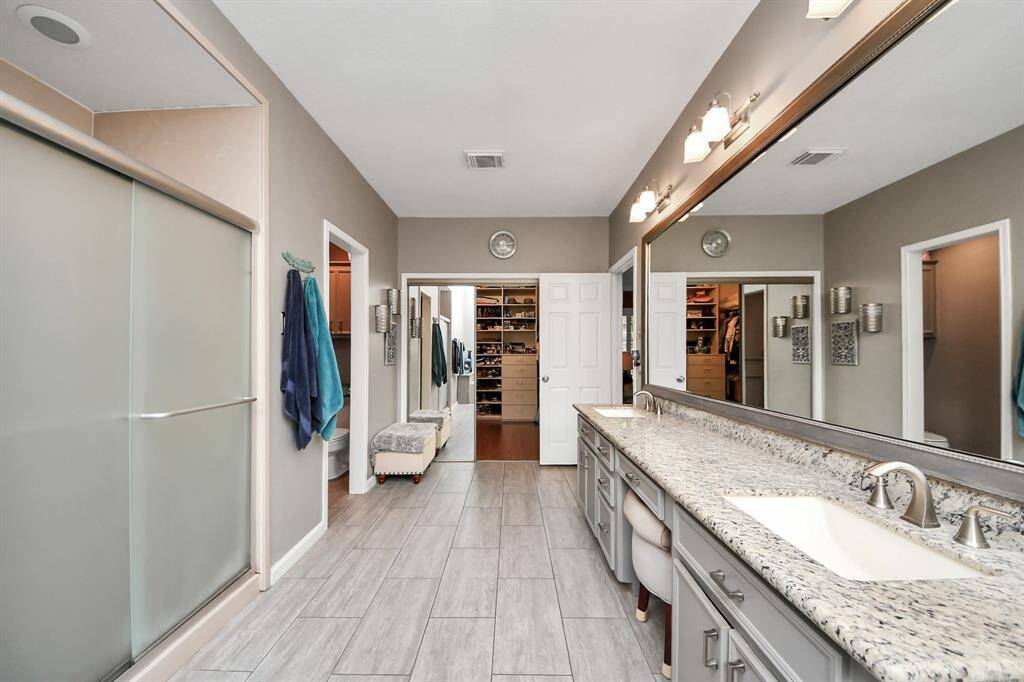Dual sinks and a dedicated vanity space with framed mirrors offer both function and style, while extensive countertop space provides ample room for makeup and personal products.
