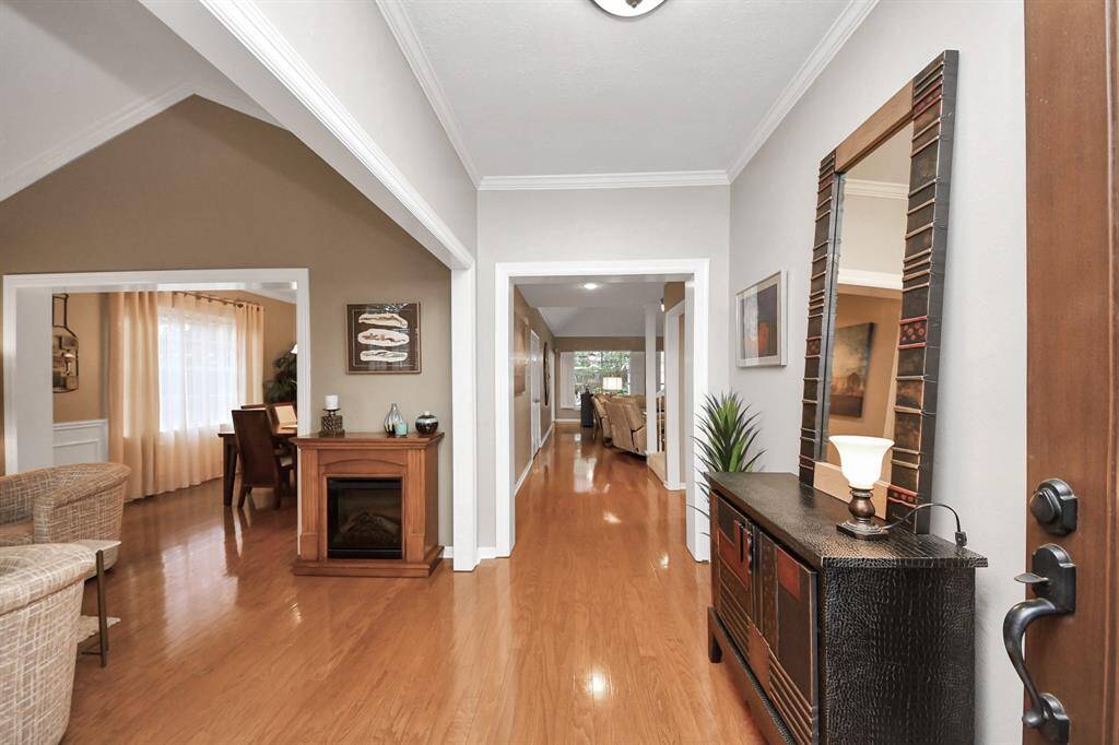 Warm wood floors greet you upon entry, complemented by a neutral color palette, open-concept design, and elegant crown molding.