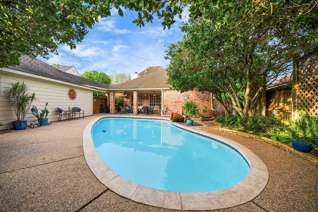 A lush backyard, beautifully landscaped with vibrant greenery and landscape lighting, offers a tranquil retreat