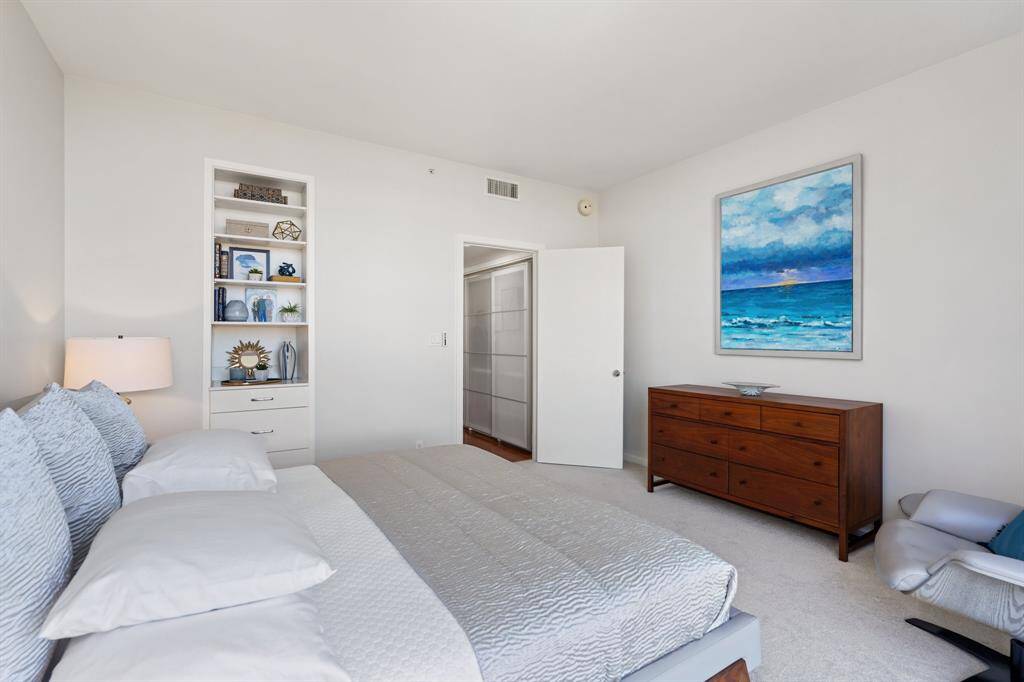 Bedroom with built-in shelving and automatic solar shades.