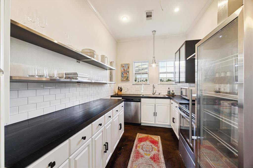 You will love this stylish kitchen with subway tile backsplash, open shelving and a glass panel refrigerator.