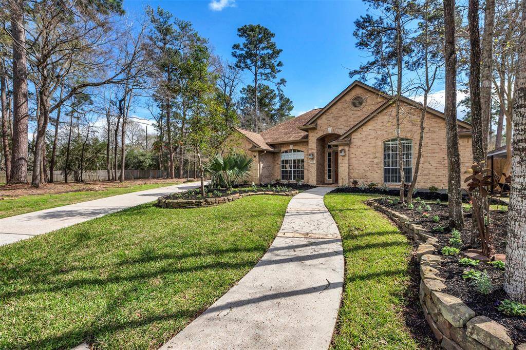This photo showcases a charming brick home with a well-maintained front yard. A curved walkway leads to the entrance, surrounded by lush greenery and mature trees, offering a welcoming and serene atmosphere.