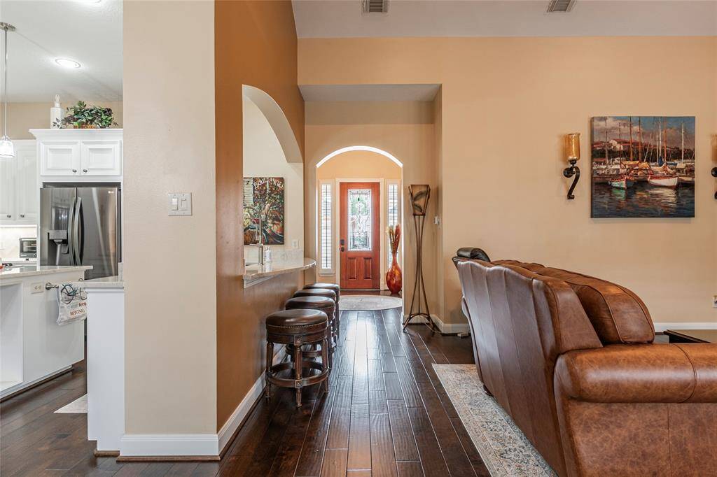 This welcoming home features an open-concept living space with warm, neutral tones and hardwood flooring. The entryway leads into a cozy living area with elegant wall sconces.