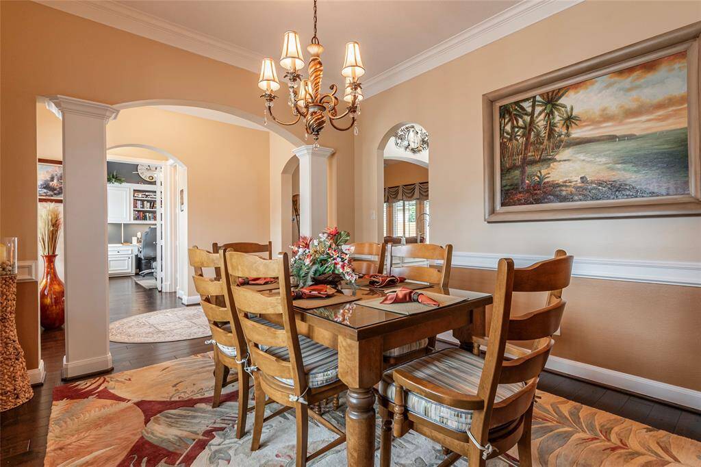 Another view of formal dining room with direct access to the kitchen, stylish chandelier, and coastal-themed paint.  Arched doorways provide access to adjacent rooms, enhancing the open flow of the space.