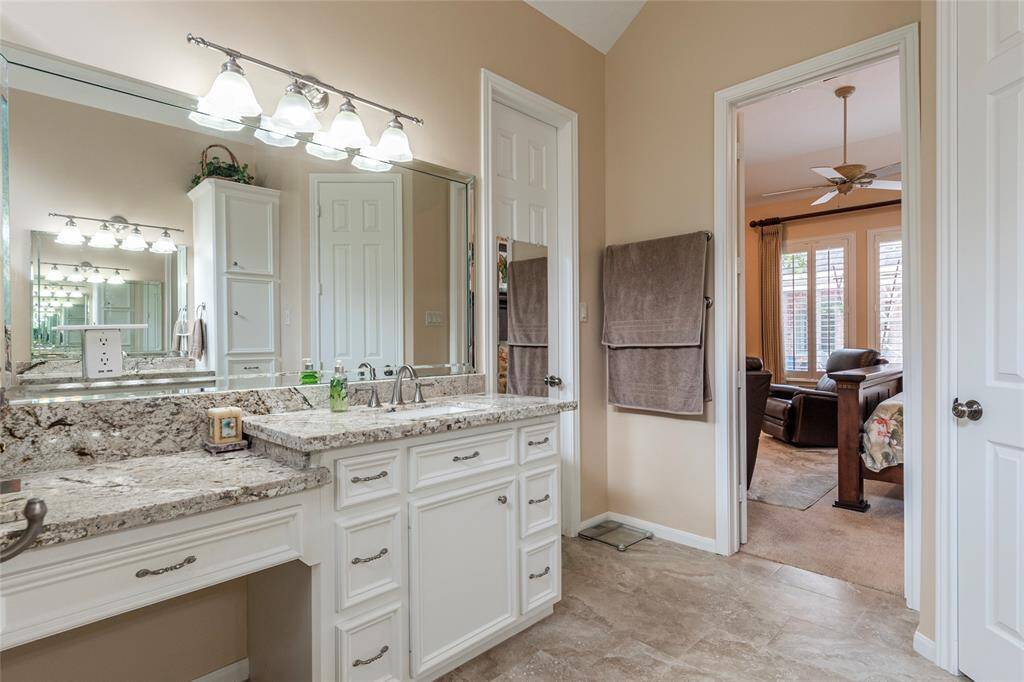 Large dual vanities with granite countertops and ample lighting enhances the space's functionality and style.