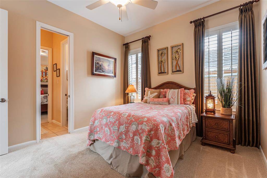 Cozy bedroom featuring a walk-in closet, space for a queen-size bed and more; large windows with shutters, and tasteful decor. The room has an en suite bathroom and a ceiling fan for added comfort.