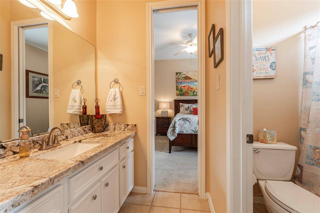 Full guest bathroom is bright and well-lit with  granite countertop, double sinks, and tub/shower combo. The bathroom features modern fixtures and tasteful decor, creating an inviting and functional space.