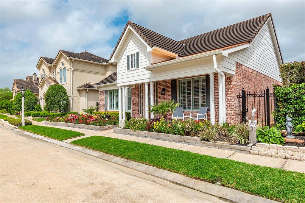 Front view of the charming brick home with a cozy porch, surrounded by well-maintained landscaping and colorful flowers. The neighborhood appears quiet and inviting, with neatly trimmed lawns and classic architecture. Ideal for those seeking a welcoming and picturesque community.