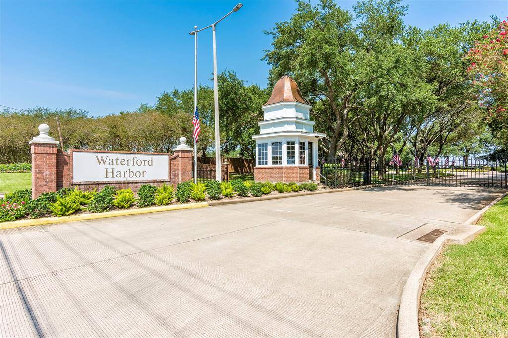 This photo showcases the entrance to Waterford Harbor, featuring a gated entry with a charming brick guardhouse and lush landscaping, suggesting a secure and well-maintained community.