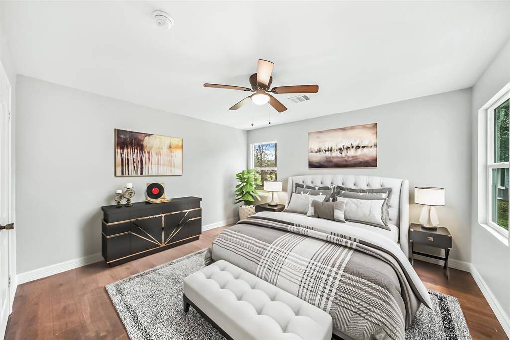 Virtually Staged: Wonderfully appointed secondary bedroom, featuring neutral paint, engineered wood floors, a ceiling fan, large windows, and a built-in closet.