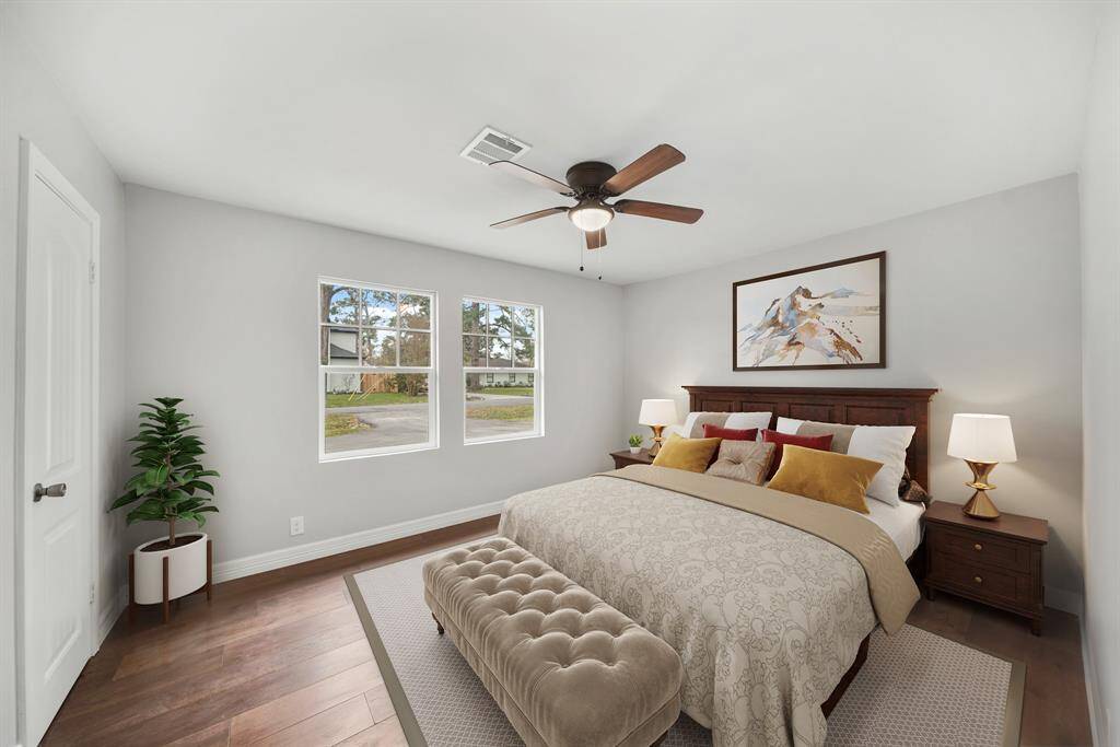 Virtually Staged: Secondary bedroom featuring neutral paint, engineered wood floors, a ceiling fan, large windows, and a built-in closet.