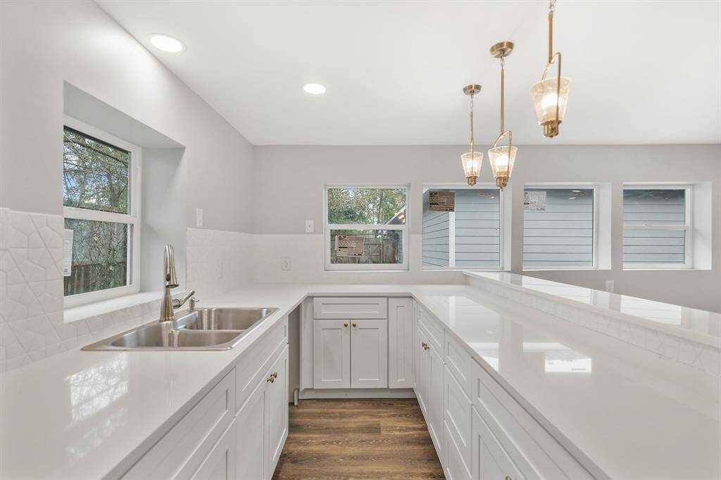 The kitchen includes recessed and pendant lighting, engineered wood floors, and plenty of counter space.