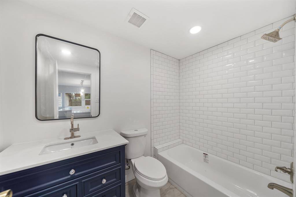 The bathroom in the guest house includes tile floors, recessed lighting, granite countertops, and a shower/tub combo.