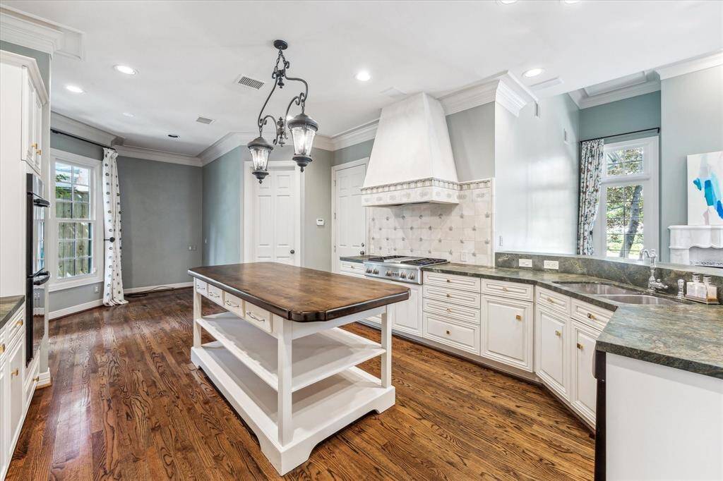 The incredible kitchen boasts a large gas stove with a griddle, double ovens, a paneled refrigerator, and a massive wood-topped island. With ample counter space and cabinetry, it caters to the needs of even the most discerning chefs.