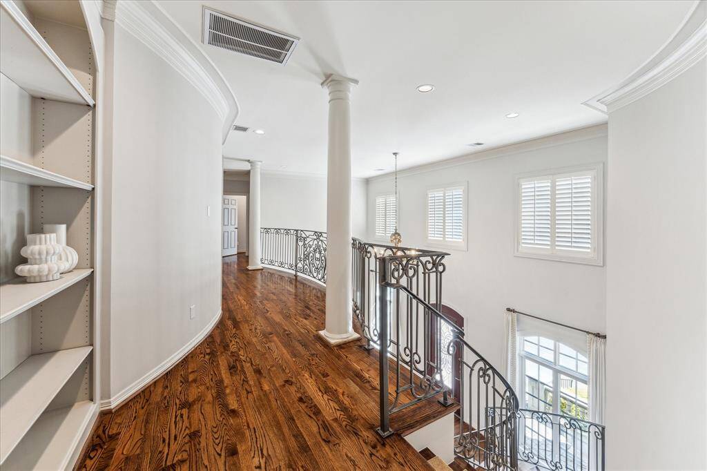 As you ascend the intricate iron staircase, you'll enjoy a bird's-eye view of the grand entryway. The upstairs landing also features built-in cabinets, adding both functionality and charm to the space