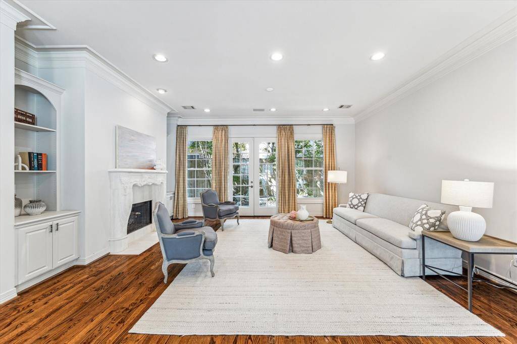 A beautiful gas log fireplace, flanked by elegant built-ins on either side, adds warmth, grace, and sophistication to the room. Additionally, double French doors open to a charming outdoor patio, complete with a delightful water feature, creating a perfect spot for relaxation and enjoyment.