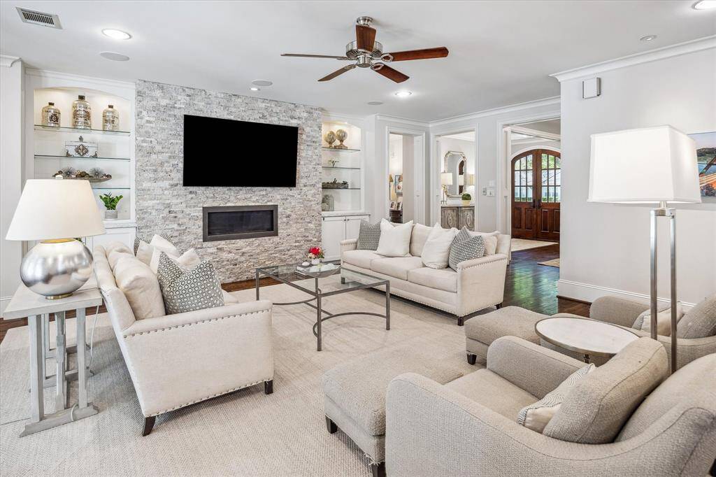Cozy living room with a gas fireplace, elegant shelving, ample storage cabinets, recessed lighting, and built-in ceiling speakers for an enhanced ambiance.