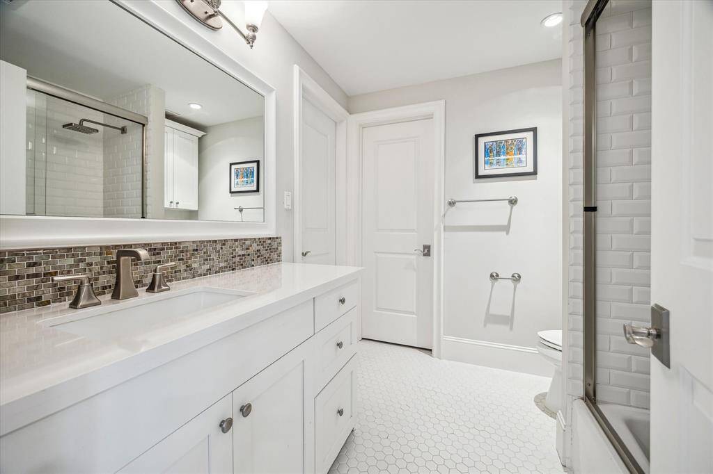 Attached full bathroom featuring a tub/shower combo with sliding glass doors. The door to the left leads to the bedroom; the door ahead opens to the walk-in closet.