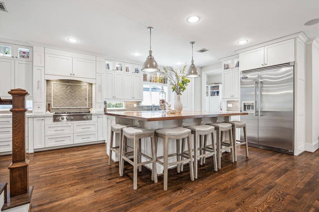 Take a look at the impressive chef’s kitchen, the heart of the home, featuring stainless steel appliances, marble countertops throughout, and a large kitchen island with butcher block countertops.