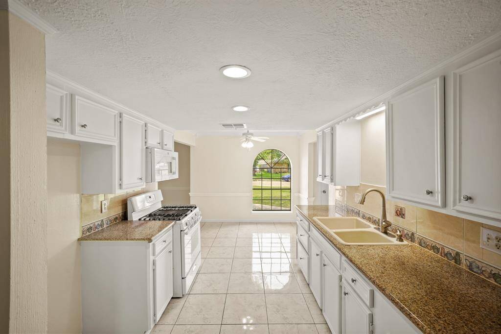 To the right of the entry is your kitchen. Features include granite countertops paired with a coordinating backsplash, high end appliances, crisp white cabinets with updated hardware, with tons of lighting.