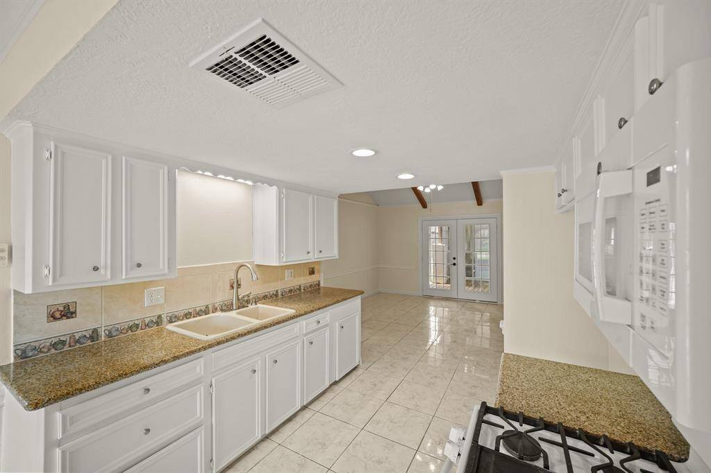Crisp white cabinets with updated hardware provide a clean and timeless look, enhancing the sense of brightness and openness in this space.