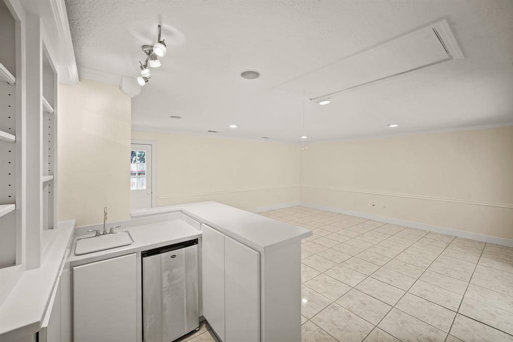 The wet bar includes a beverage refrigerator, sleek countertop and custom cabinets, offering a stylish and convenient space for serving drinks and snacks.