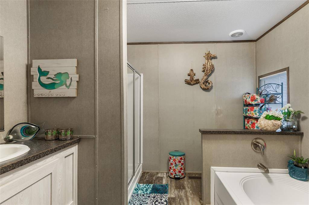 This bathroom features a modern design with a walk-in shower and a large soaking tub. It has a neutral color palette, accented with ocean-themed decor and vibrant floral patterns, creating a relaxing and inviting atmosphere.