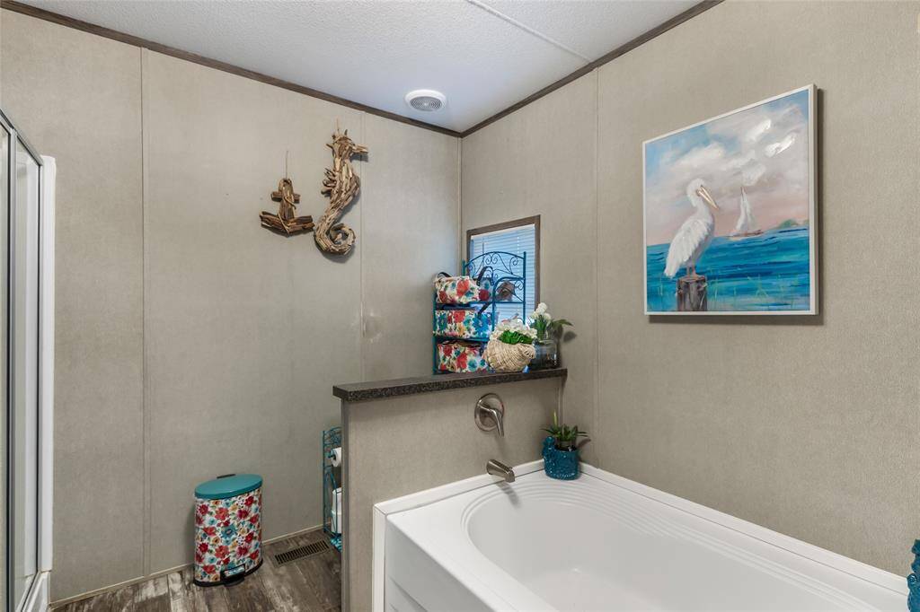 This bathroom features a relaxing bathtub with nautical decor, including a pelican painting and a seahorse wall sculpture. The space is brightened by a small window and colorful accents, creating a cozy and inviting atmosphere.