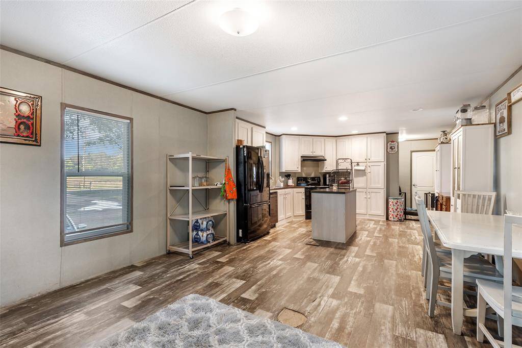 This photo showcases a spacious, open-concept kitchen and dining area with modern appliances, ample cabinetry, and wood-style flooring. Natural light streams through a window, enhancing the bright and inviting atmosphere.