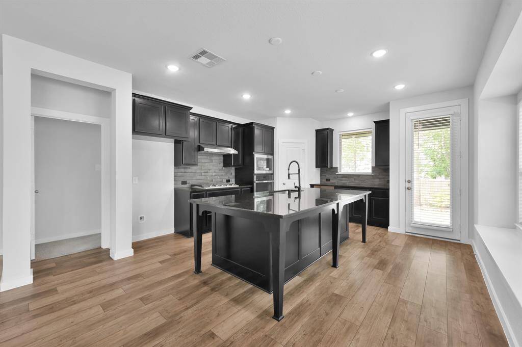 The gourmet kitchen features granite countertops, upgraded cabinetry, and a large center island with room to gather.