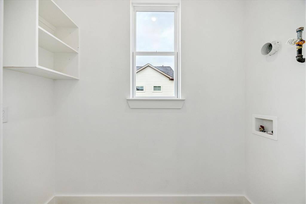 The laundry room is located between the second and third floor. This laundry room has a shelf, a hanging bar and a window.
