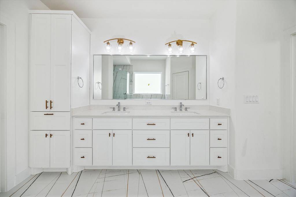 Expansive primary suite bathroom with upgraded Shaker style, soft close cabinets and designer tile and double sinks.