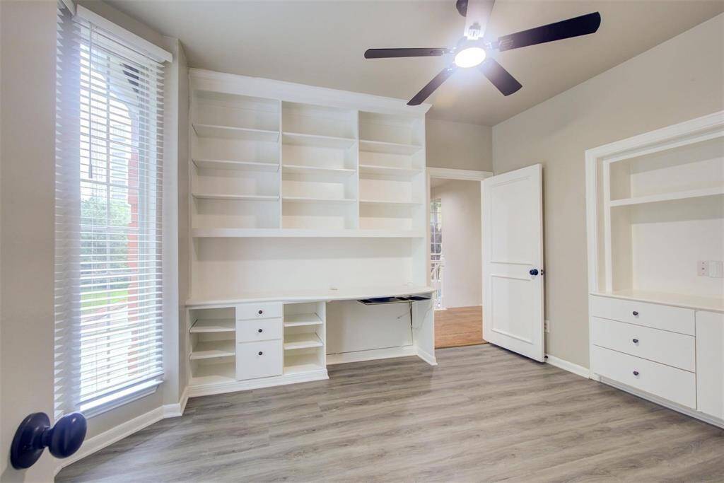 Bedroom 2 with a wall of built in shelves and desk on 1 wall and dresser on the other wall