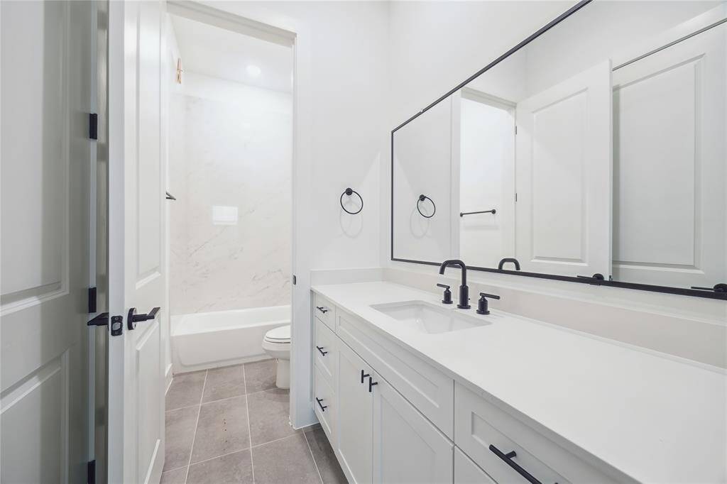 Beautiful quartz, and seamless designer tile in another one of your bathrooms with shower/tub.