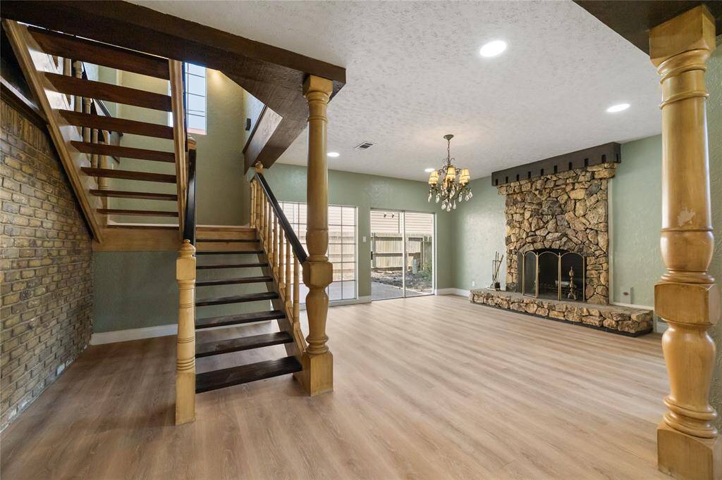 This cozy den, located just off the formal dining area, features a stunning stone fireplace and a sliding glass door that leads to the backyard. A chandelier is centered above the room, adding a touch of elegance to the space.