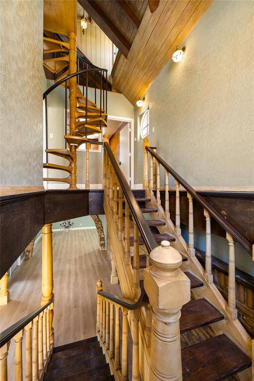 The custom stairs leading to the second floor are designed with a gentle incline, making them easy to climb. There is a spacious landing area that offers a moment of rest before continuing up. The image also showcases the custom spiral staircase that connects the second floor to the third-floor loft area, adding a unique touch to the home’s design.