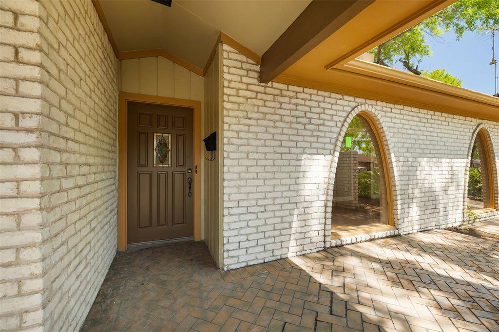 Beautiful brick exterior featuring custom large arched windows that offer a glimpse into the welcoming receiving area. The exterior flooring showcases an elegant herringbone brick pattern, adding timeless charm to the home's facade.